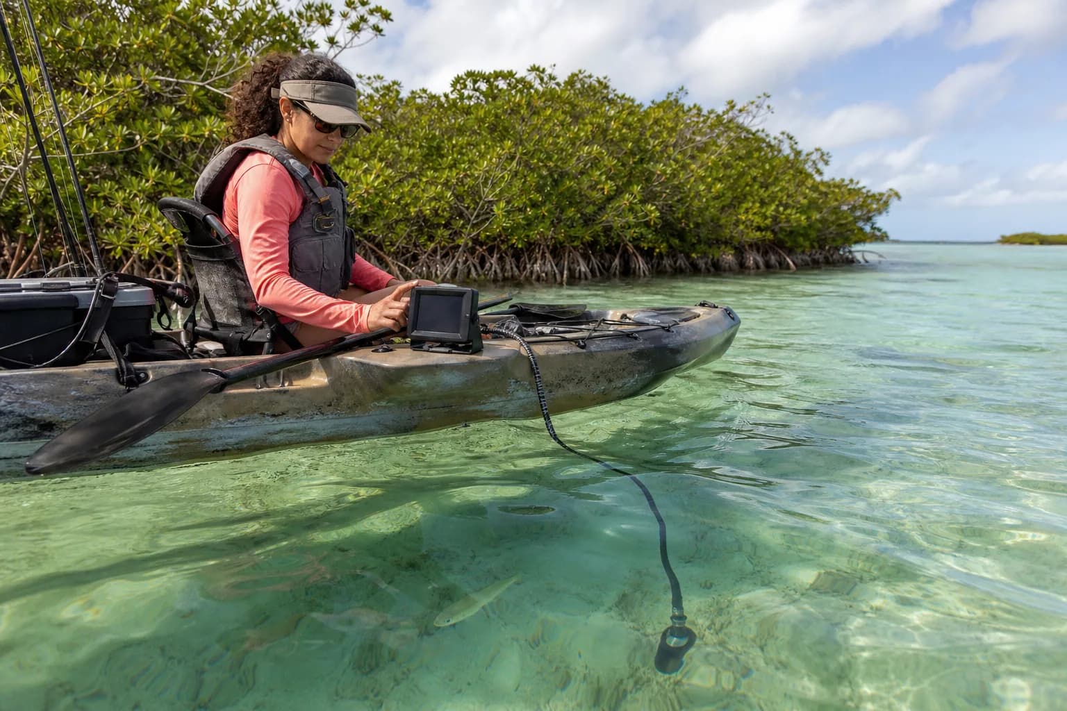 Woman viewing an underwater camera monitor from a kayak on tropical flats